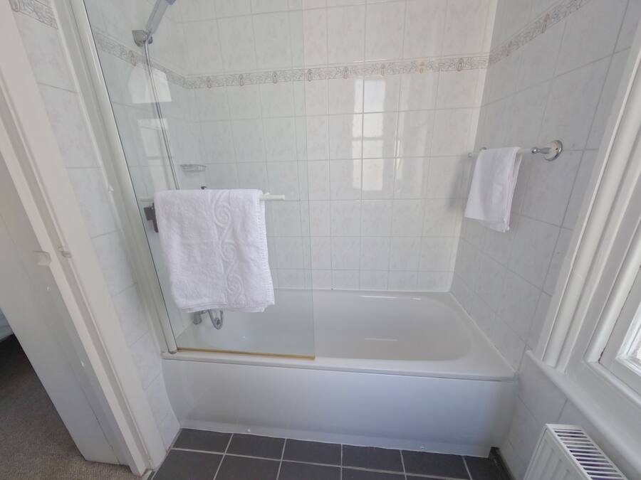 Ein Badezimmer mit einer Duschkabine, einer weißen Badewanne und einem weißen Handtuch an einem Haken.