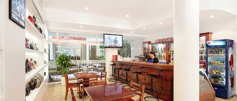 A restaurant with wooden tables and chairs, a bar area, shelves with handbags, and a Pepsi refrigerator.