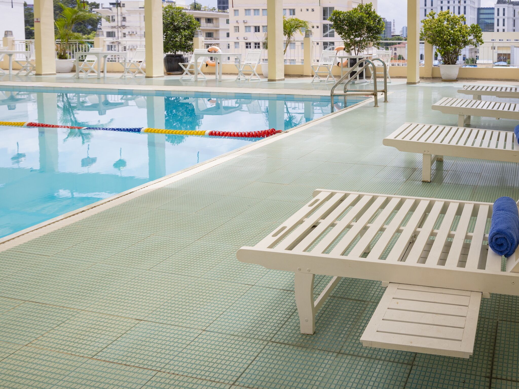 An indoor swimming pool with clear lane dividers, lounge chairs, and a tiled deck.