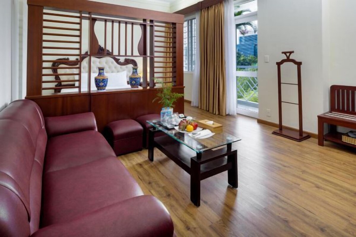 Um quarto com um sofá vermelho, uma mesa de centro de vidro e um divisório de madeira tradicional.