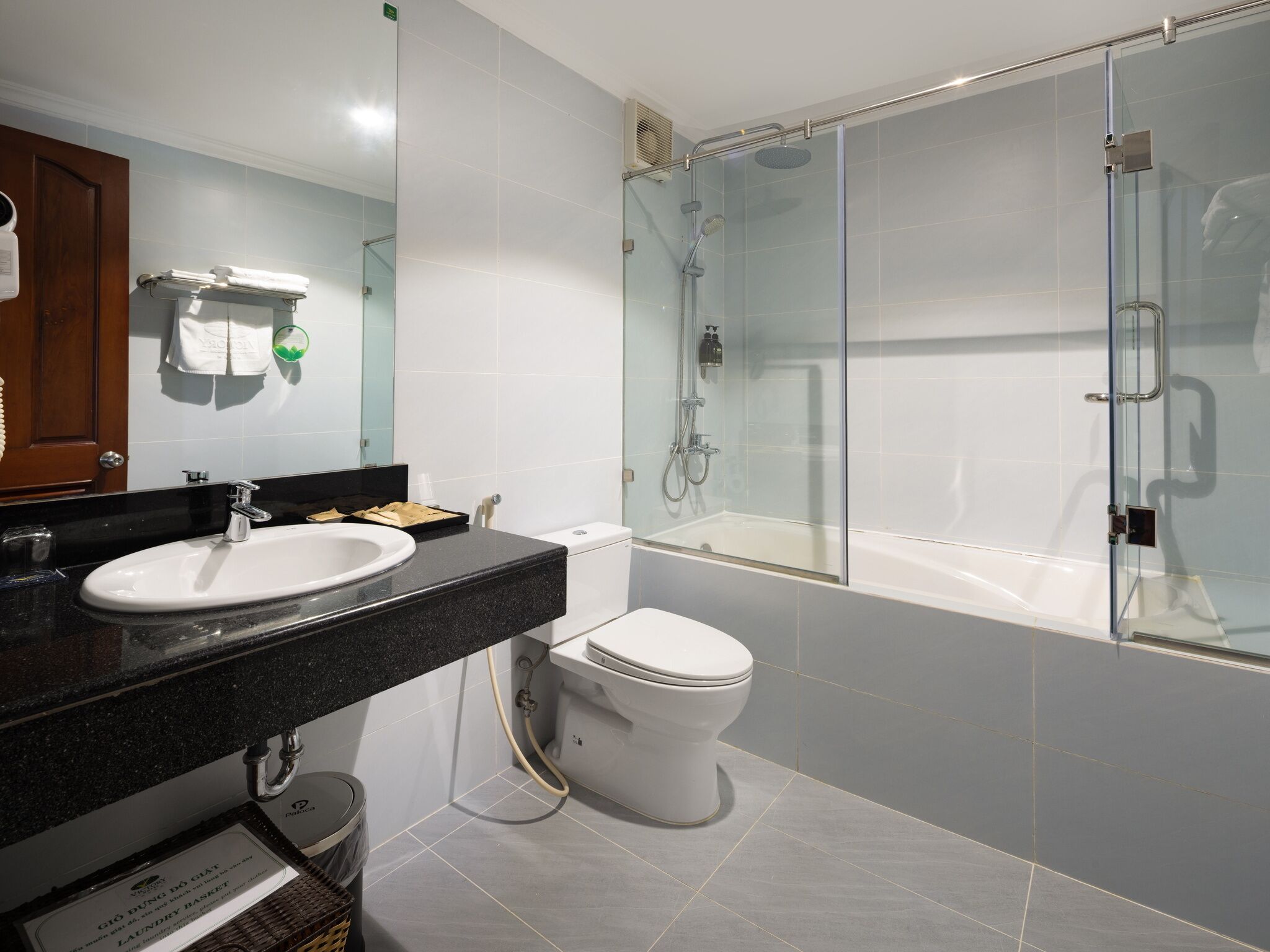 Un baño moderno con ducha acristalada, inodoro blanco y encimera negra con lavabo.