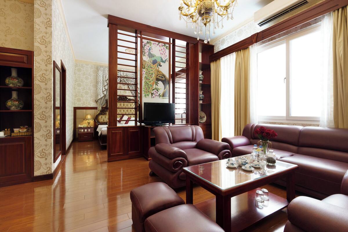 A living room with a brown leather sofa, a glass coffee table, and a television.