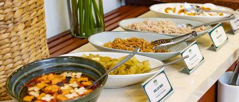 A buffet with various dishes including pickled cucumber, noodles, and a bowl of mixed vegetables.