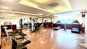 A gym with various exercise equipment, a large window, and a polished floor. - Victory Saigon Hotel (Ho Chi Minh City)