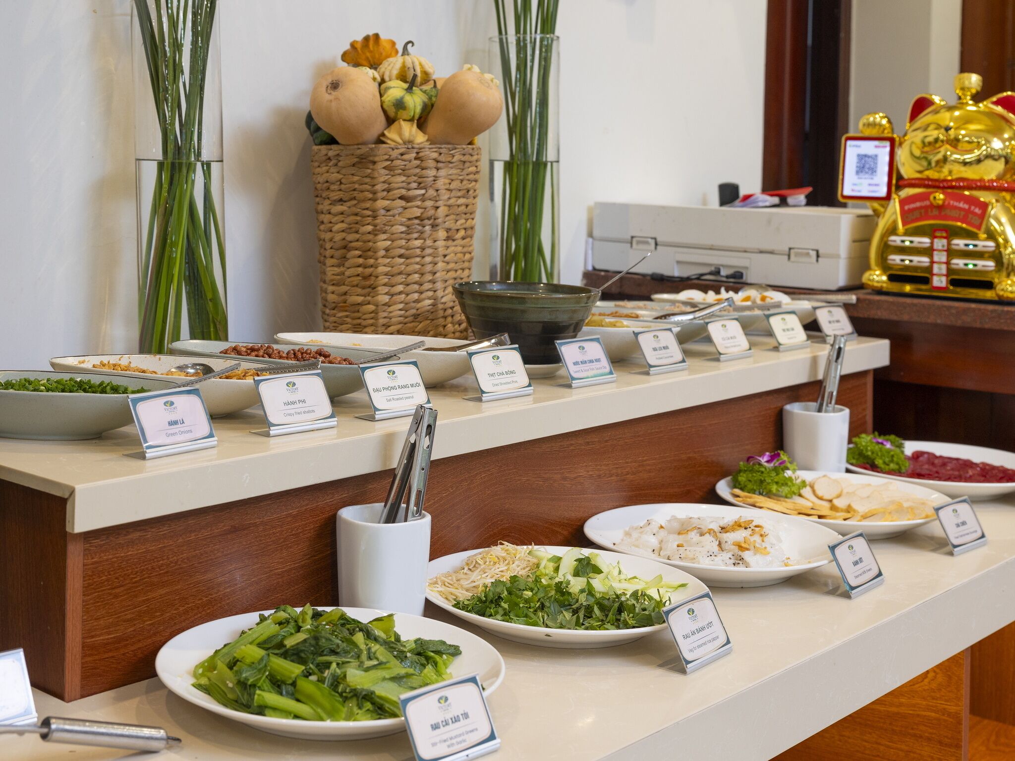 A buffet with various dishes labeled, including green onions, crispy fried shallots, and a salad with bean sprouts.