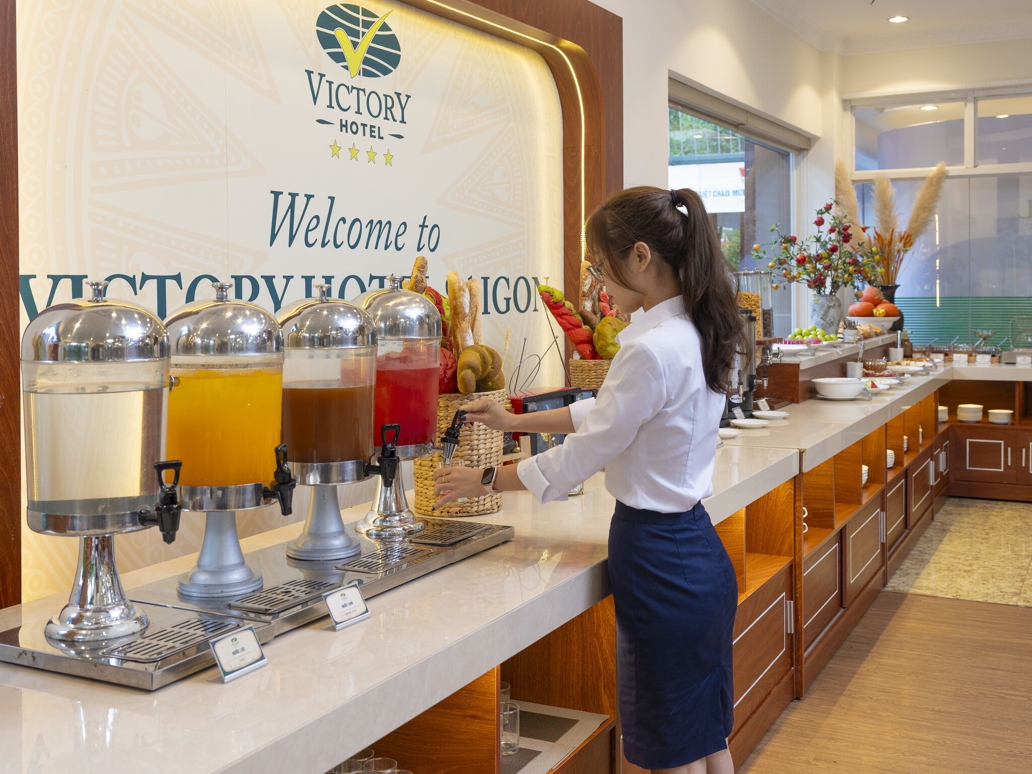 A buffet setup at Victory Hotel with multiple beverage dispensers and a variety of food items.