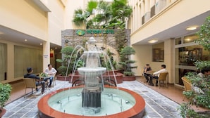 A hotel courtyard with a central fountain, seating areas, and a stone wall with greenery. - Victory Saigon Hotel (Ho Chi Minh City)