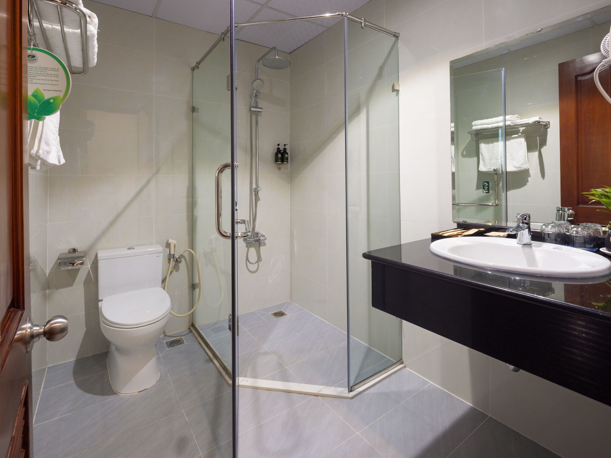 Une salle de bain moderne avec une douche à parois de verre, des toilettes blanches et un meuble-lavabo noir avec un miroir.