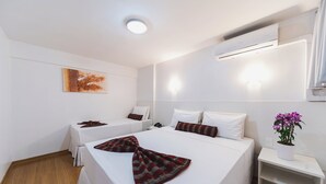 A hotel room with two beds, a ceiling light, an air conditioning unit, and a small nightstand with a potted plant. - Hotel Nacional Inn Curitiba Estação Shopping (Curitiba)