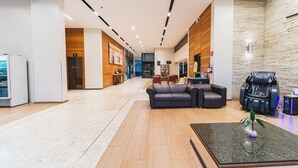 A spacious lobby with a modern design, featuring a seating area with a sofa and armchairs, a massage chair, and a reception desk. - Hotel Nacional Inn Curitiba Estação Shopping (Curitiba)