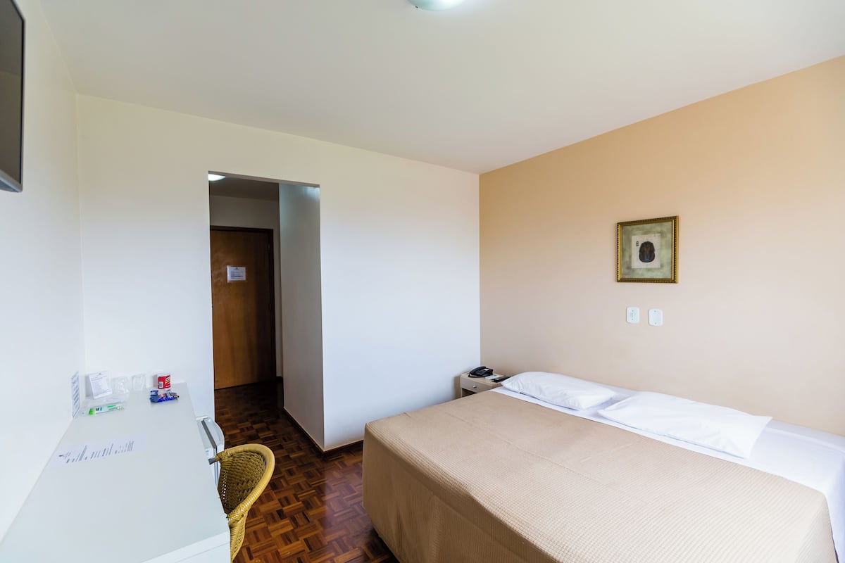 Une chambre d’hôtel comprenant un lit, un bureau, une chaise et une porte donnant sur une autre pièce.