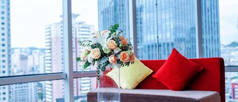 Et moderne værelse med en rød sofa, et glasbord og en blomstervase.