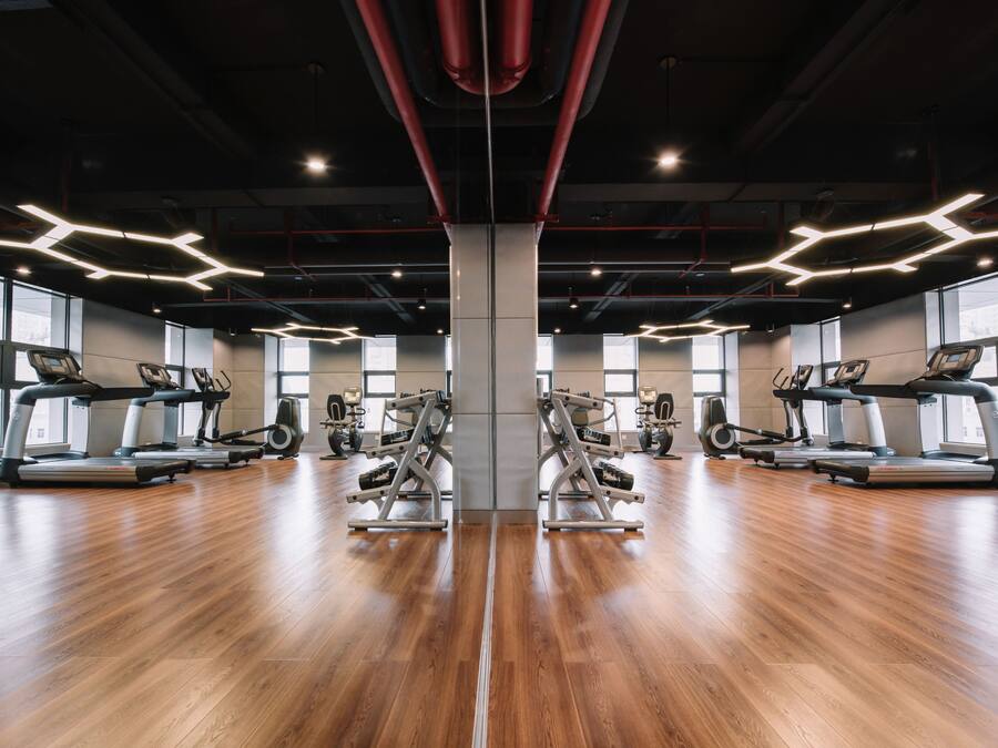 A gym with mirrored walls, treadmills, and weight machines.