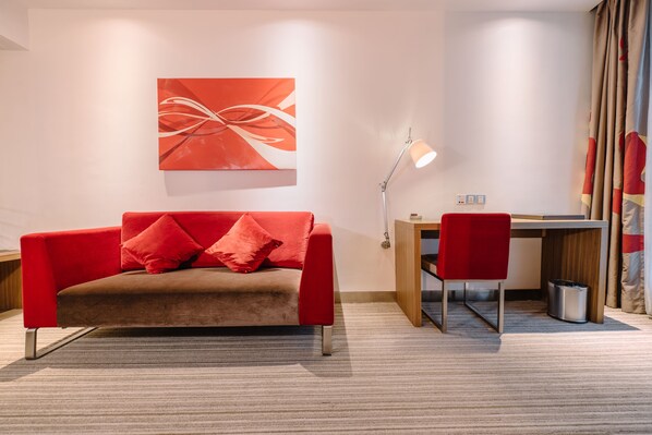 A modern room with a red sofa, a desk, and a chair. - Novotel Guiyang Downtown (Guiyang)
