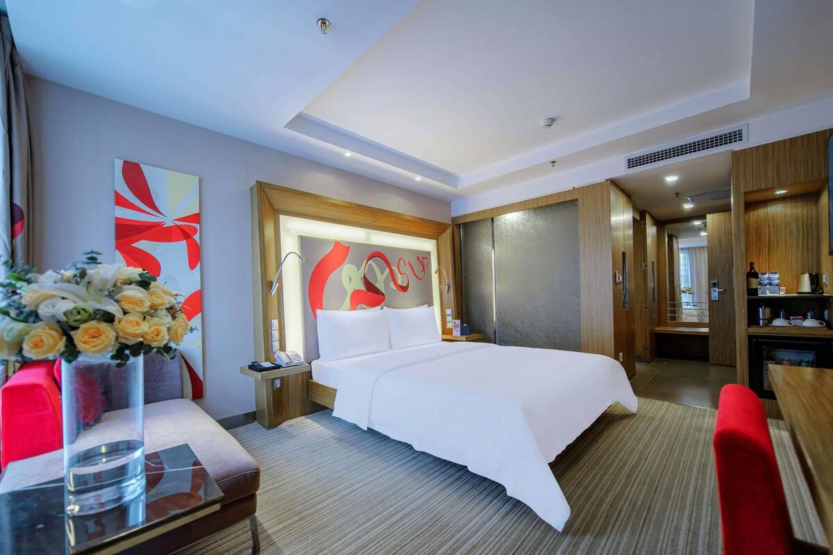 Ein Hotelzimmer mit Bett, Nachttisch, Lampe und einer Wanddekoration.