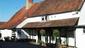 A traditional white building with a tiled roof and a covered porch area. - The George & Dragon (Devizes)