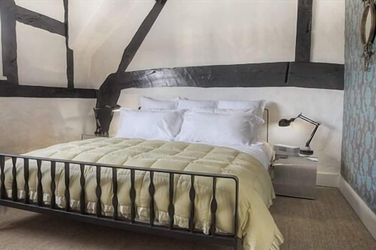 Un dormitorio con cama, mesita de noche y lámpara.