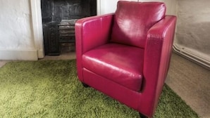 A room with a red leather armchair, a white fireplace, and a green carpet. - The George & Dragon (Devizes)
