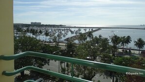 A marina with boats, palm trees, and a distant view of a bridge and cityscape.