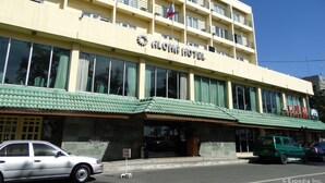 A hotel with a flat facade, multiple balconies, and a green awning.