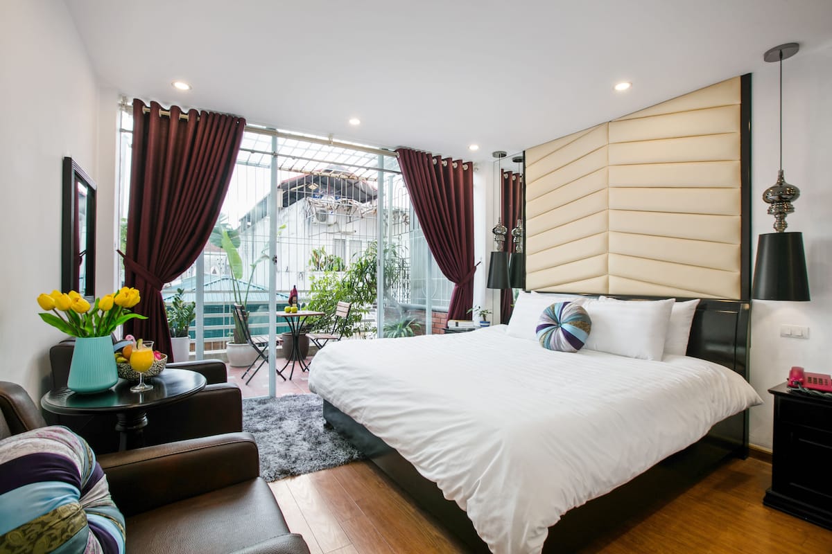 A modern bedroom with a large bed, a seating area with a coffee table, and a view of the outside.