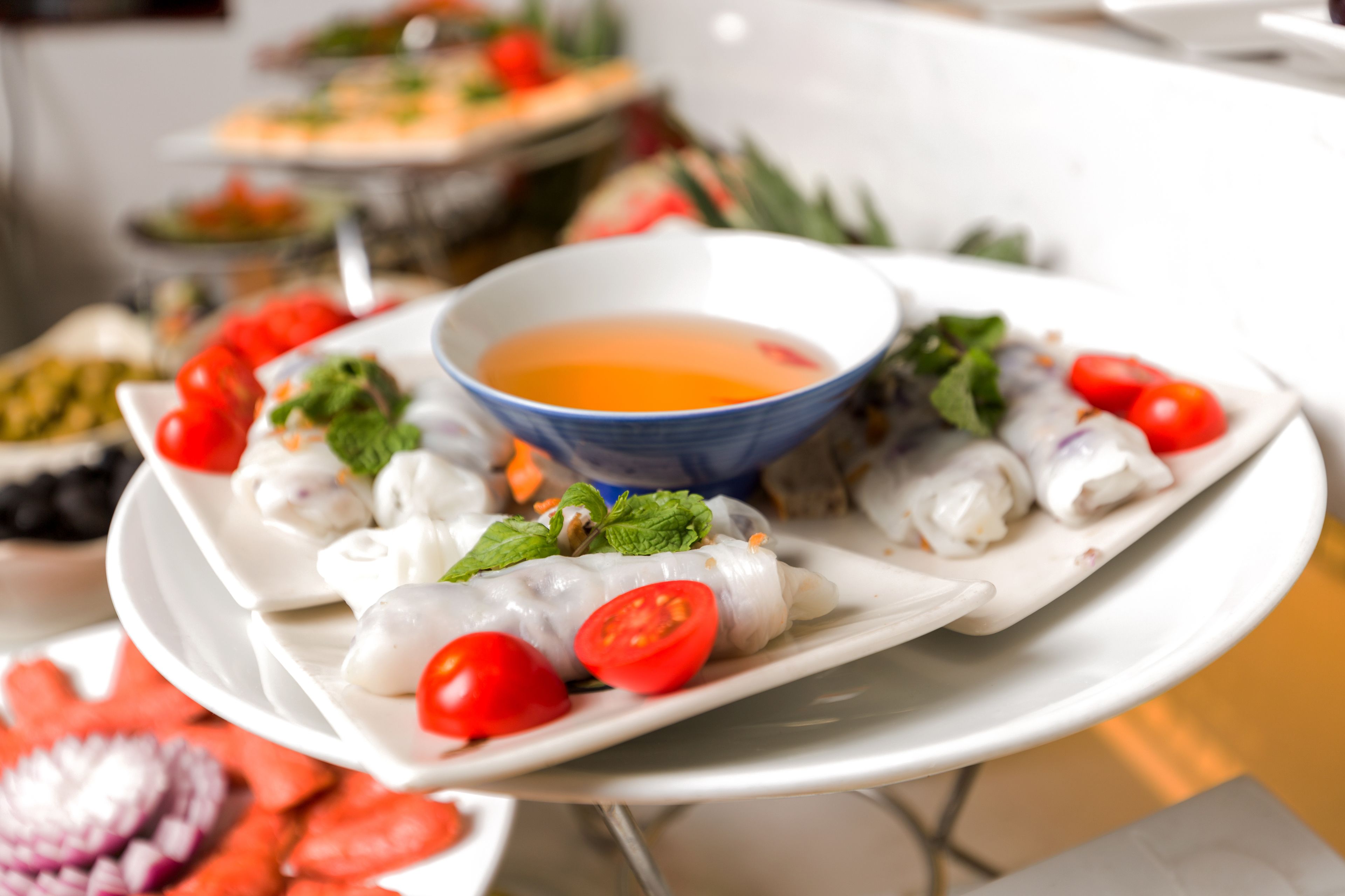 A plate of spring rolls with a bowl of dipping sauce.