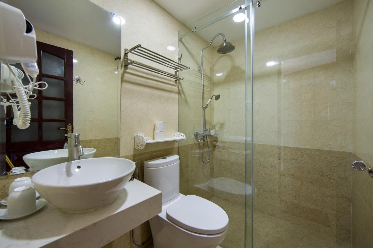 A bathroom with a glass-enclosed shower, a white sink, and a toilet.