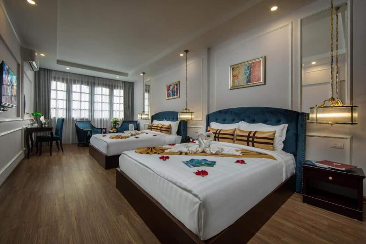 A hotel room with two beds, a desk, and a chair.