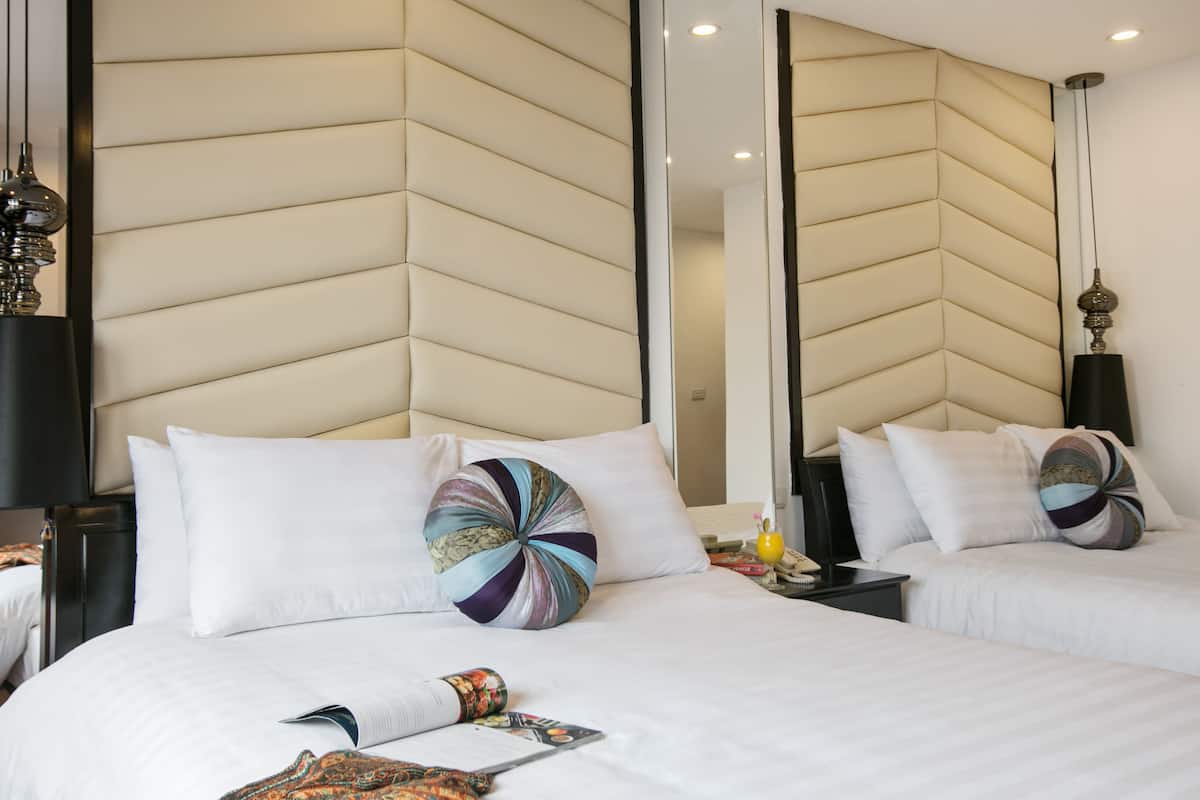 A hotel room with a large bed, two bedside tables, a nightstand, and a mirror.