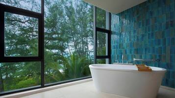 A modern bathroom with a freestanding bathtub, large windows, and a blue mosaic wall.