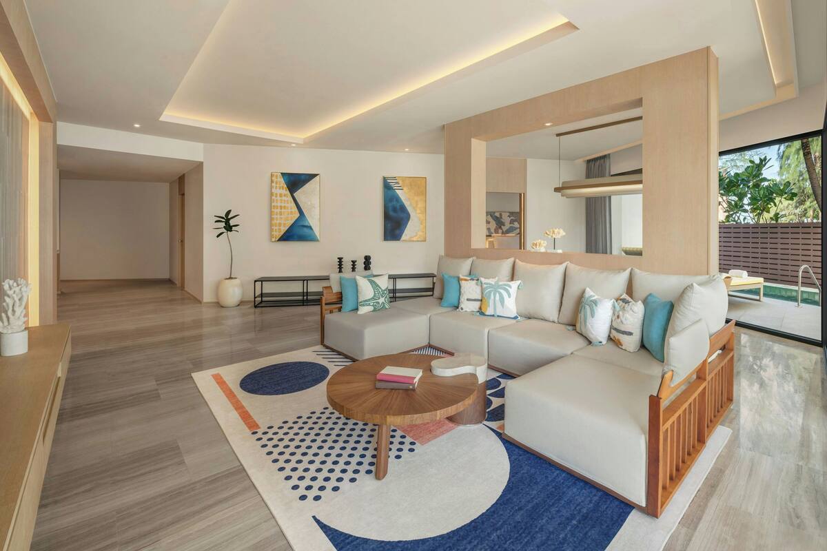 A modern living room with a sectional sofa, a round coffee table, and abstract wall art.