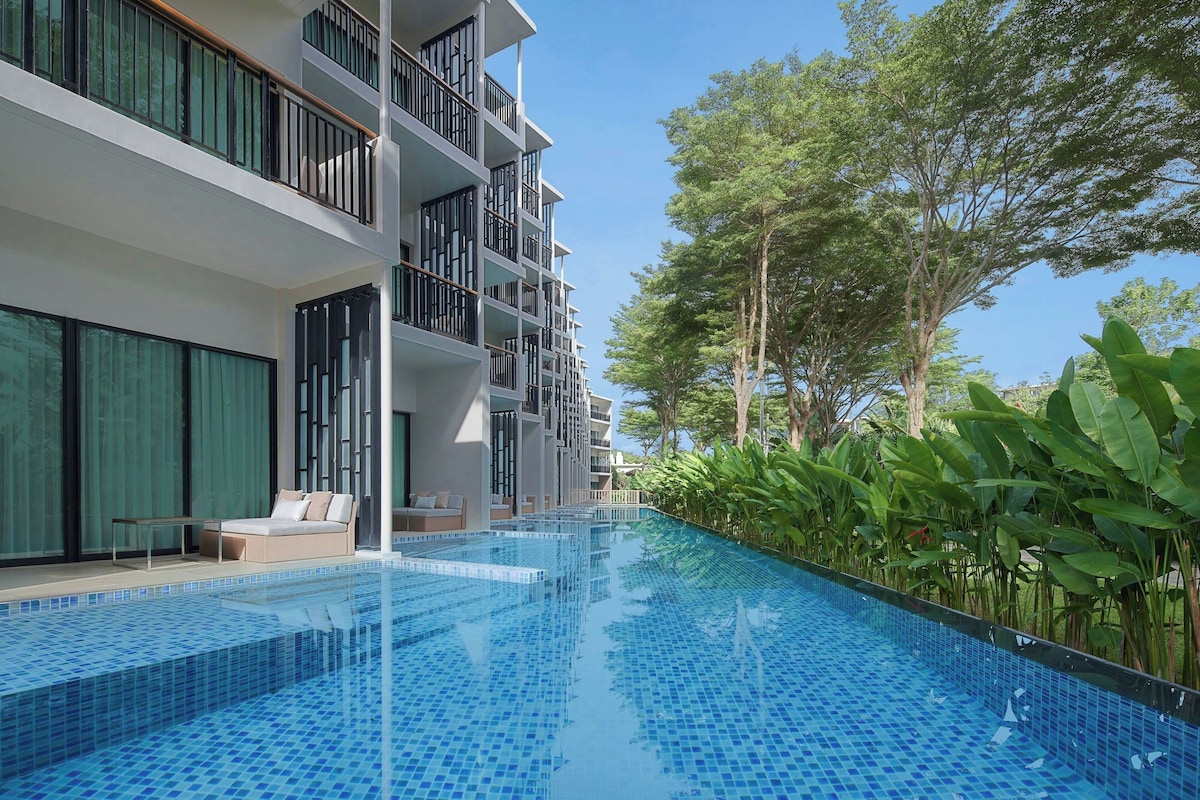 Um hotel moderno com piscina, área de estar ao ar livre e vegetação exuberante.