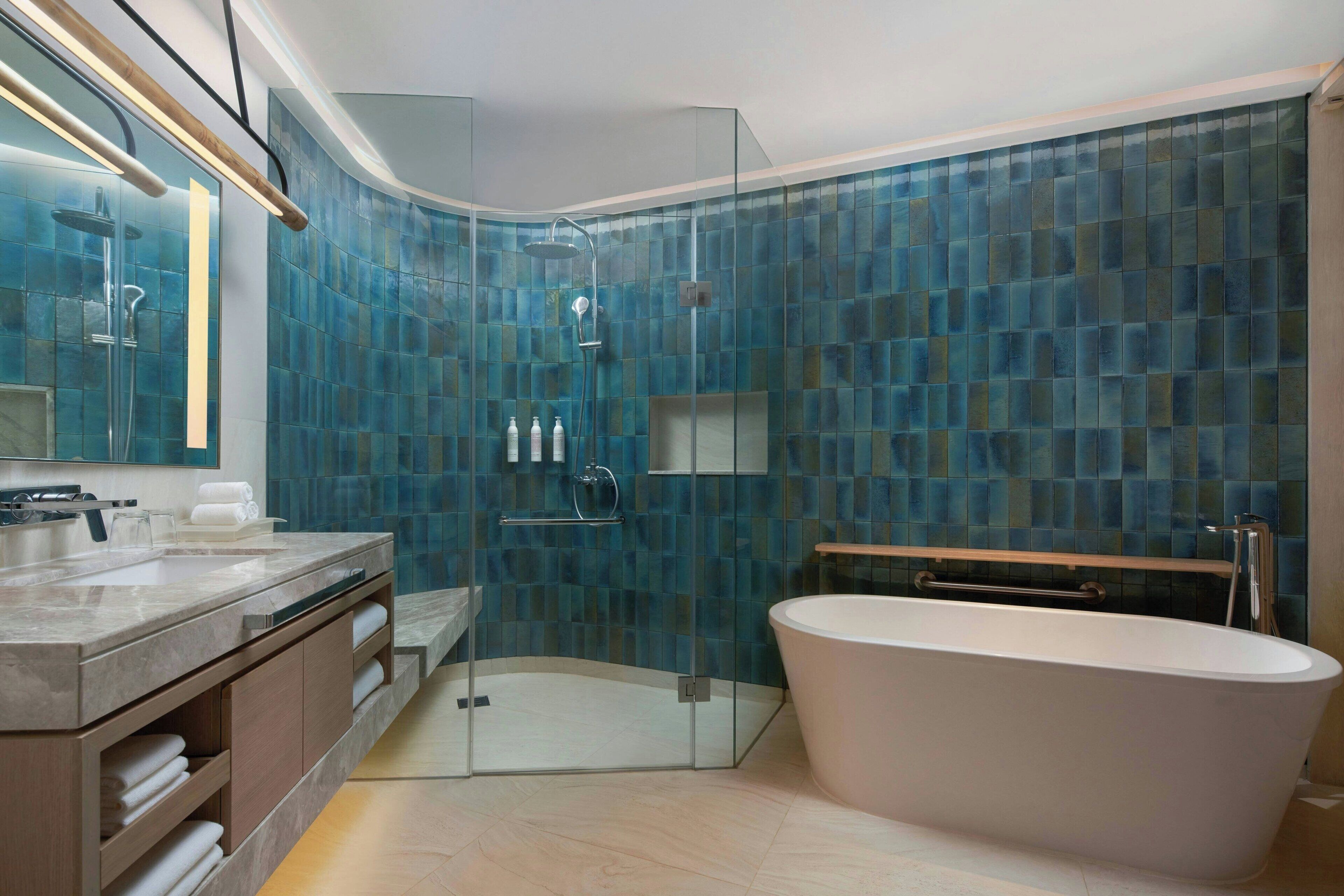 A modern bathroom with a glass-enclosed shower, a freestanding bathtub, and a vanity with a mirror and towel rack.