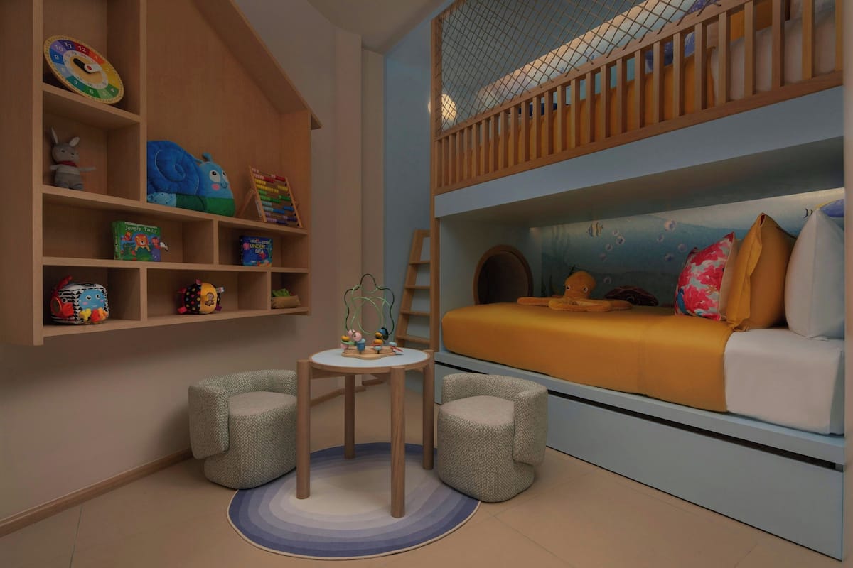 A child's bedroom with a bunk bed, shelves with toys, a small table, and a play area.