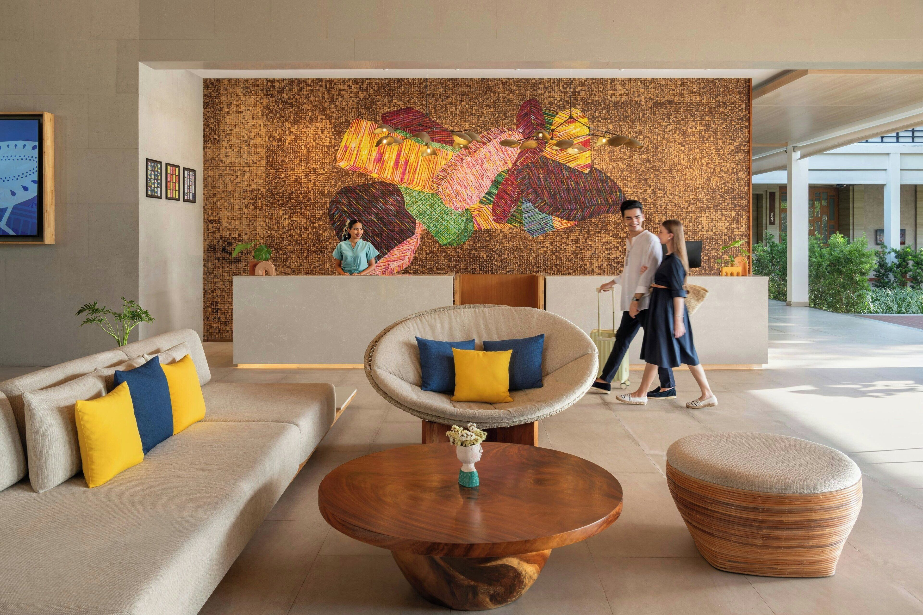 A modern lobby with a large abstract mural, comfortable seating, and a reception desk.