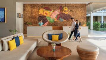 A modern lobby with a large abstract mural, comfortable seating, and a reception desk.
