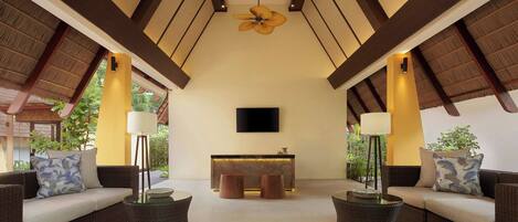 A spacious lounge area with a high ceiling, a central reception desk, and comfortable seating arrangements.