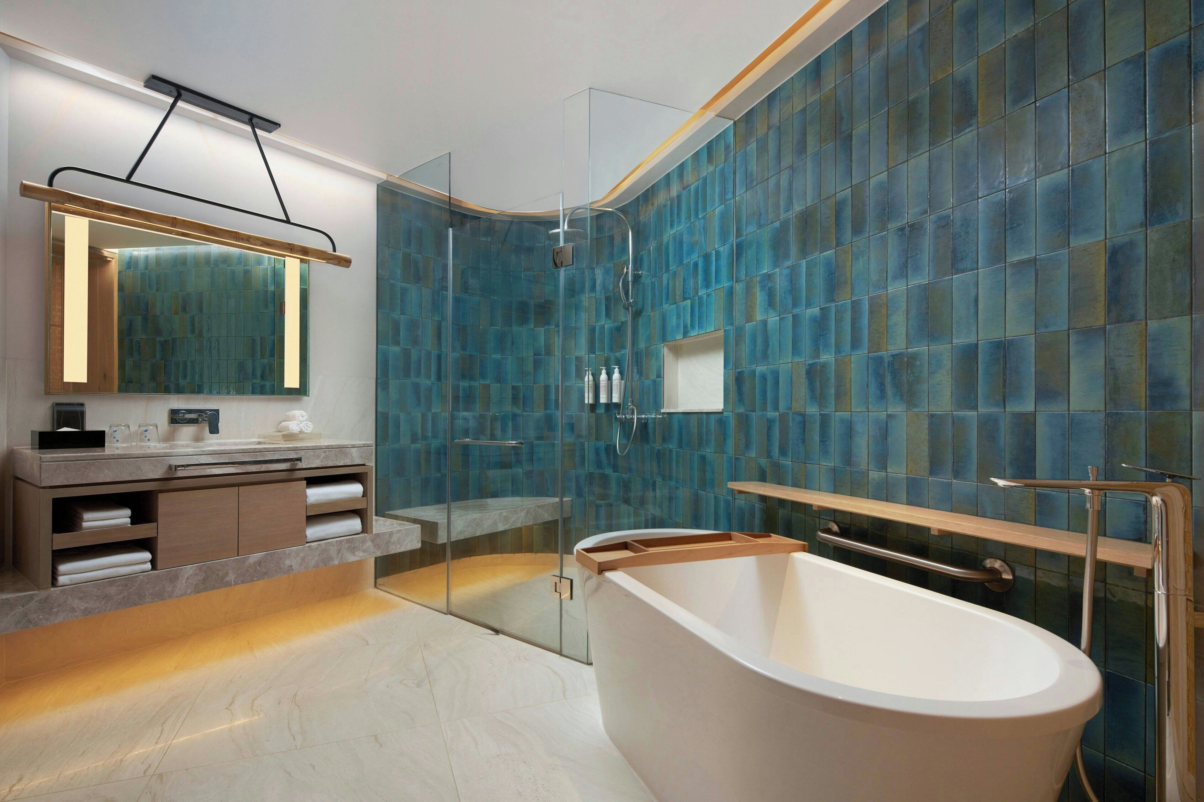 A modern bathroom with a freestanding bathtub, a glass-enclosed shower, and a vanity with a mirror and towel racks.