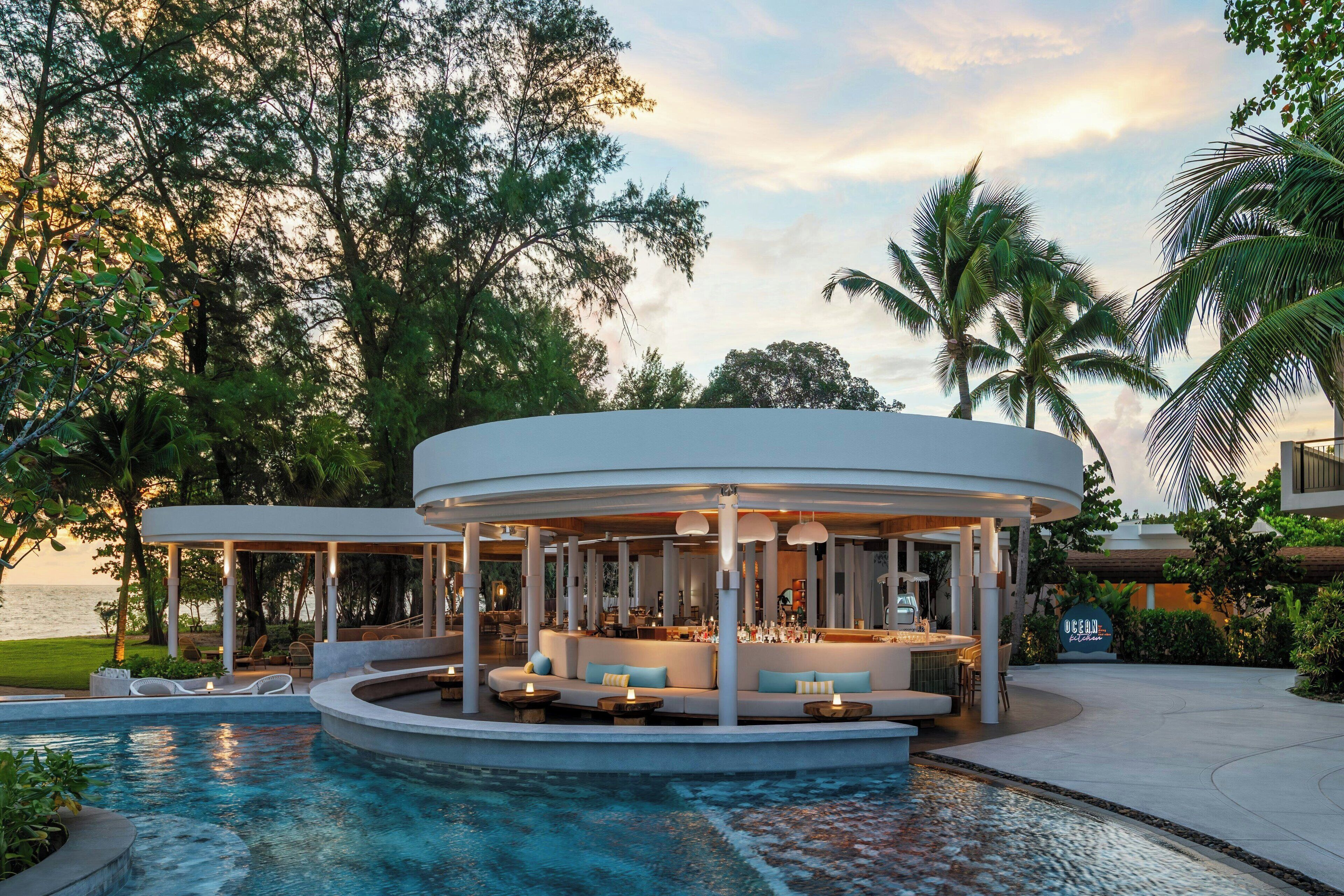 A poolside lounge with a circular seating area, a bar, and a view of the ocean.