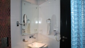 A modern bathroom with a white sink, a large mirror, a hairdryer, and a towel rack. - Baba Inn (New Delhi)