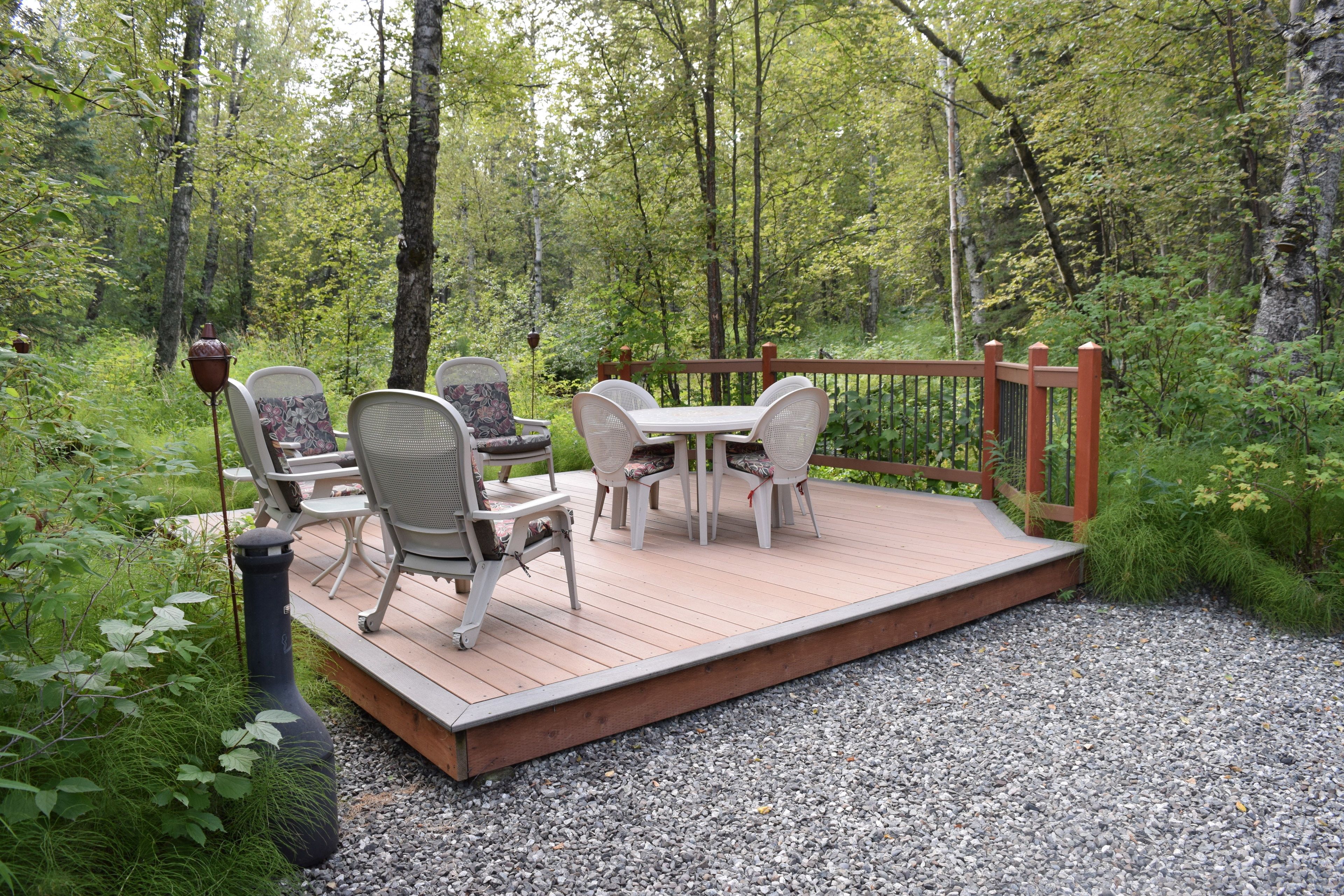 Una terraza con mobiliario exterior, rodeada de un bosque.