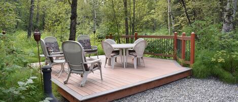 Una terraza con mobiliario exterior, rodeada de un bosque.