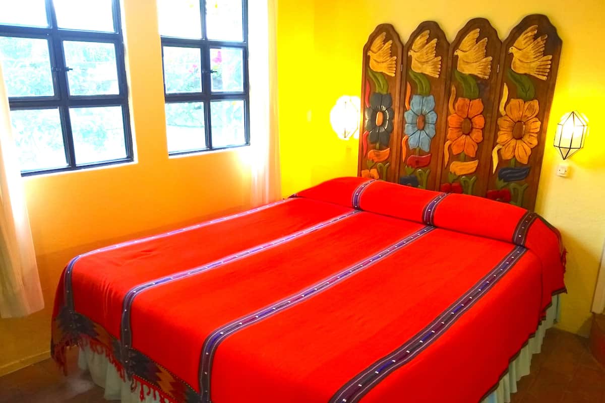 Una habitación con una cama grande, un ventanal y una pared con un panel decorativo.