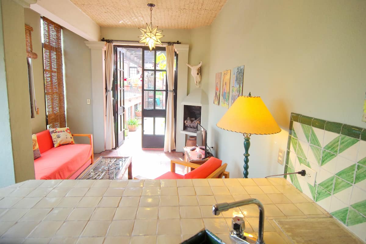 Una habitación con suelo de baldosas, un sofá, una mesa, una lámpara y vistas al exterior a través de una puerta.