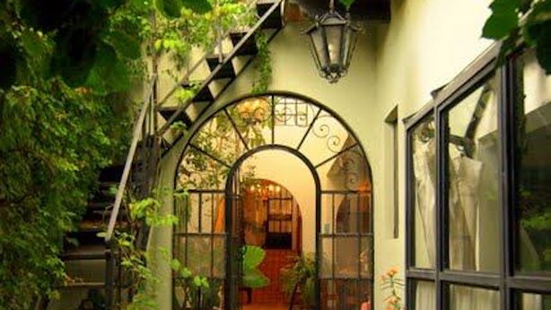 A staircase leading to a room with a stone floor, a window with a curtain, and a door with an arch design.
