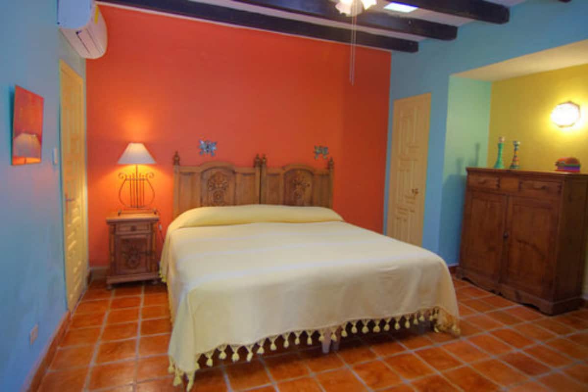 Un dormitorio con una cama, una mesita de noche, una lámpara y un armario de madera.