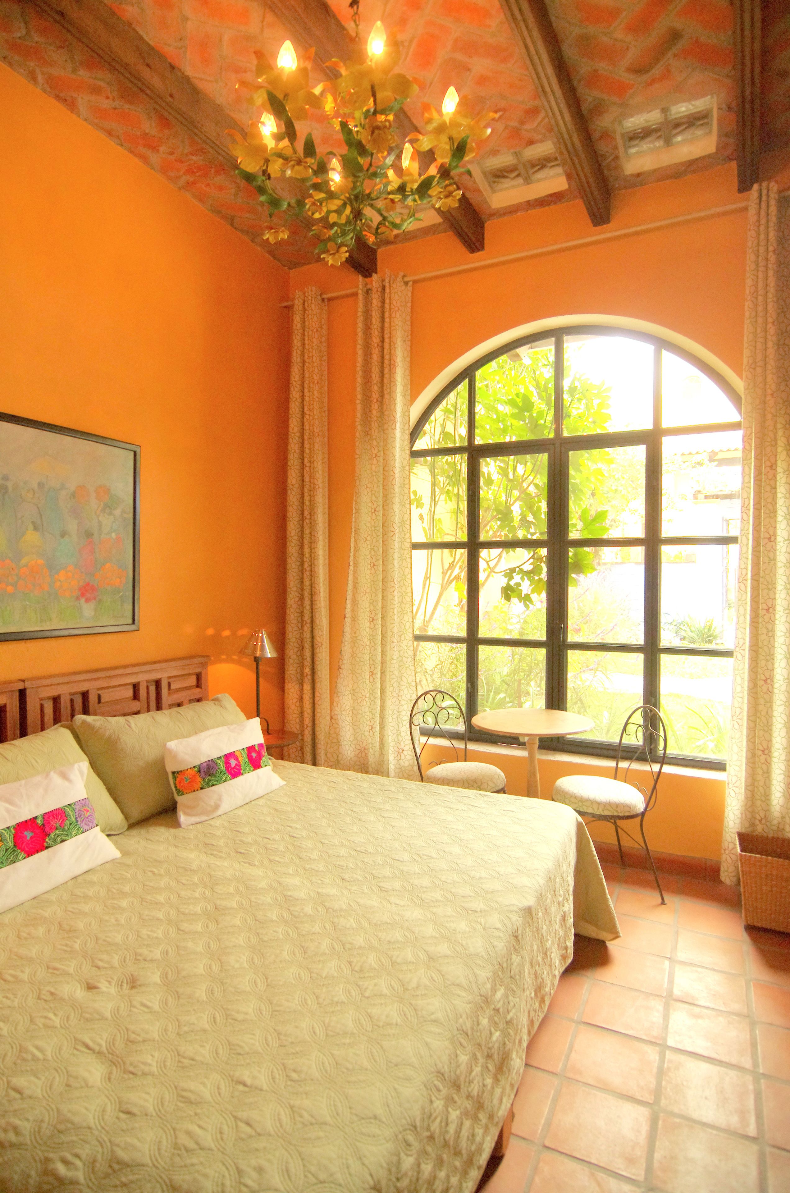 Una habitación con una cama, una ventana, una silla y una mesa.