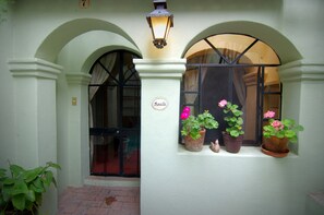 A building entrance with a sign reading "Rosita," three potted plants on the windowsill, and a street lamp above. - Casa de la Noche (San Miguel de Allende)