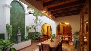 A cozy dining area with a wooden table and chairs, surrounded by plants and a patterned rug.