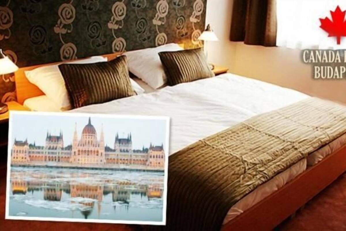 Habitación de hotel con cama, almohadas, lámpara y un cuadro del parlamento de Budapest.